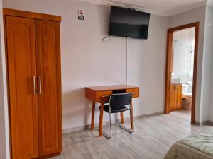 1 dormitorio con escritorio y TV en la pared en Hostal Morlaquita, en Cuenca