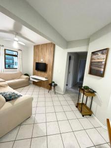 uma sala de estar com um sofá e uma televisão em Apto com ótima localização, centro de Meia Praia em Itapema