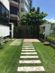 a grass yard with a stone pathway in front of a building at Apto com ótima localização, centro de Meia Praia in Itapema