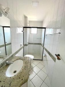uma casa de banho com um lavatório, um chuveiro e um WC. em Apto com ótima localização, centro de Meia Praia em Itapema
