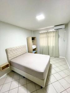 um quarto com uma cama branca num quarto em Apto com ótima localização, centro de Meia Praia em Itapema