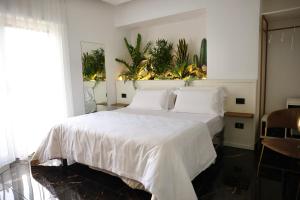 een slaapkamer met een wit bed met planten aan de muur bij Hotel Max in Aversa