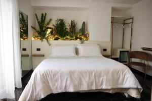 a bedroom with a white bed with plants on the wall at Hotel Max in Aversa