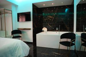 een slaapkamer met een bed, een bad en stoelen bij Hotel Max in Aversa