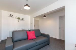 sala de estar con sofá azul y almohada roja en Cherry Property - Cranberry Suite en Blackpool