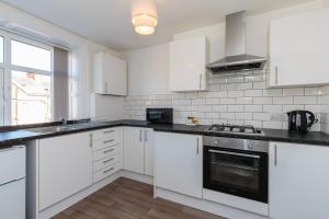 a white kitchen with white cabinets and a stove at Cherry Property - Cranberry Suite in Blackpool