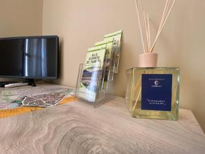 a table with a bottle of perfume and a tv at Chicco Apartment Small Business in Vercelli