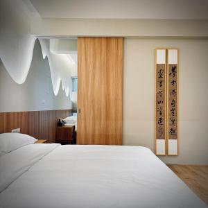 1 dormitorio con cama blanca y puerta de madera en 沐正農場 嘉義包棟民宿 en Zhongpu