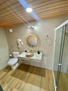 a bathroom with a toilet and a mirror on the wall at Pousada Yapara-Tyba in Japaratinga