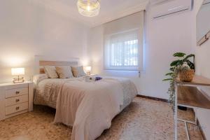 a white bedroom with a bed and a window at Chalet a pie de playa in Punta Umbría