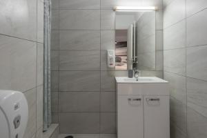 Baño blanco con lavabo y espejo en Bucharest Central Apartments - Shabbat Friendly, en Bucarest