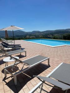 a group of tables and chairs next to a swimming pool at Agriturismo Villa Rosetta in San Severino Marche