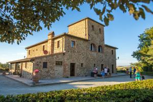 an old stone building with people standing outside at La Mandriola in Laiatico