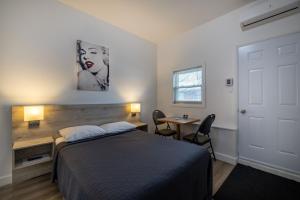 a bedroom with a bed and a desk and a table at Motel Et Condo Chez Charley in Sainte-Anne-de-Beaupré