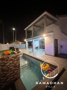 uma piscina em frente a uma casa à noite em Ramadhan Villa PD em Porto Dickson