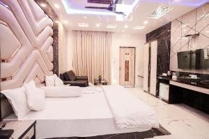 1 dormitorio con 1 cama blanca grande y TV en Bombay Beach Resort, en Mandarmani