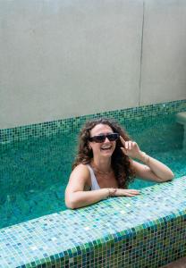 a woman in a swimming pool wearing sunglasses at Nopalero Suites Hostel in Puerto Escondido