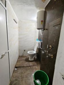 a bathroom with a toilet and a green bucket at Shivay homestay ujjain in Ujjain