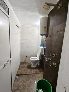 a small bathroom with a toilet and a green bucket at Shivay homestay ujjain in Ujjain