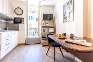 a kitchen with a wooden table and a clock on the wall at FRGK " Charming Studio in Historic Center of Cannes" in Cannes