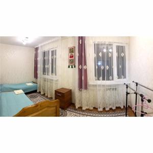 una habitación de hospital con hileras de camas y cortinas en Janat Family Guesthouse, en Karakol