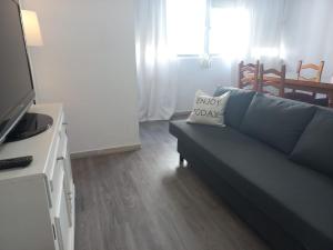 a living room with a blue couch with a pillow on it at Apartamentos céntricos a 10 min de la playa in Almería