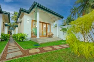 a small white house with a grass yard at The Dahlia Residence in Bentota