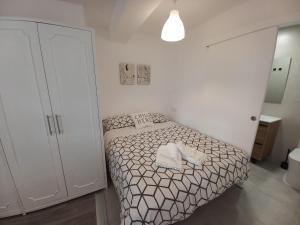una piccola camera da letto con un letto con lenzuola e cuscini bianchi di Apartamentos céntricos a 10 min de la playa a Almería