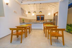 a dining room with wooden tables and chairs and a kitchen at The Dahlia Residence in Bentota
