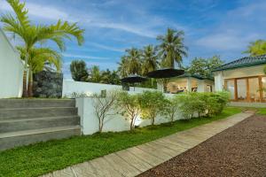 a house with a white wall and stairs and trees at The Dahlia Residence in Bentota