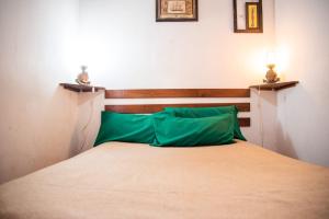 a bed with a wooden headboard and a green pillow at La Casita de Gesell in Villa Gesell