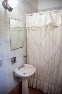 a bathroom with a white shower curtain and a sink at La Casita de Gesell in Villa Gesell