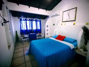 1 dormitorio con cama azul y almohada roja en Hotel Cocos, en Salinas