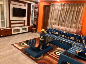 sala de estar con sofá azul y TV en Sacred Trails Homestay, en Burhānilkantha