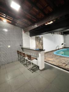 uma piscina com um bar e cadeiras num quarto em Pousada automática sem recepção 2 em Uberlândia