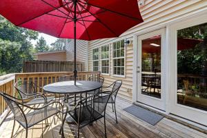 eine Terrasse mit einem Tisch, Stühlen und einem roten Regenschirm in der Unterkunft The Junction House - Near Downtown Cary & RDU in Cary