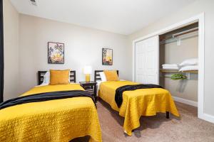 two beds in a room with yellow sheets at The Junction House - Near Downtown Cary & RDU in Cary