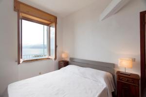 a white bedroom with a bed and a window at Seaview House Cala Gonone in Cala Gonone