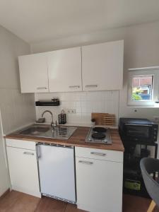 Eine Küche mit weißen Schränken, Spüle und Herd in der Unterkunft AlteFeuerwache #2 in Husum