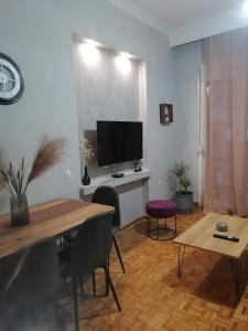 sala de estar con mesa y TV de pantalla plana en City Center Beauty, en Serres