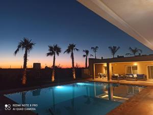 a villa with a swimming pool at night with palm trees at Bienvenu chez VillAtlas in Marrakesh