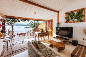uma sala de estar com um sofá e uma televisão de ecrã grande em Refúgio na natureza com vista espetacular em Ilhabela em Ilhabela