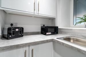 a kitchen counter with a microwave and a sink at Bell Apartment in Airdrie