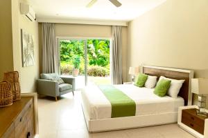 1 dormitorio con 1 cama, 1 silla y 1 ventana en Private Iberosta Villa Lagoon 4BDR- Private Beach and Pool, en Punta Cana