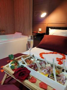 a tray of food and a glass of wine on a bed at Nuit d'évasion love room avec baignoire balnéothérapie in Toulon