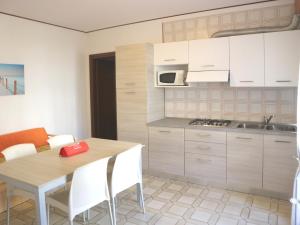 リニャーノ・サッビアドーロにあるMagnoliaのキッチン(白いキャビネット、テーブル、椅子付)
