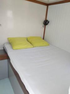 a white bed with two yellow pillows on it at L'aquahome hébergement sur l'eau in Les Trois-Îlets