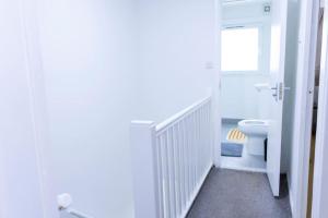 a white bathroom with a toilet and a window at Beautiful 3 bed house next to Westfield London in London