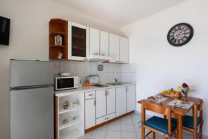 a kitchen with a refrigerator and a table and a clock at House Rasica in Molunat
