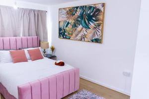 a bedroom with a pink bed and a painting on the wall at Beautiful 3 bed house next to Westfield London in London